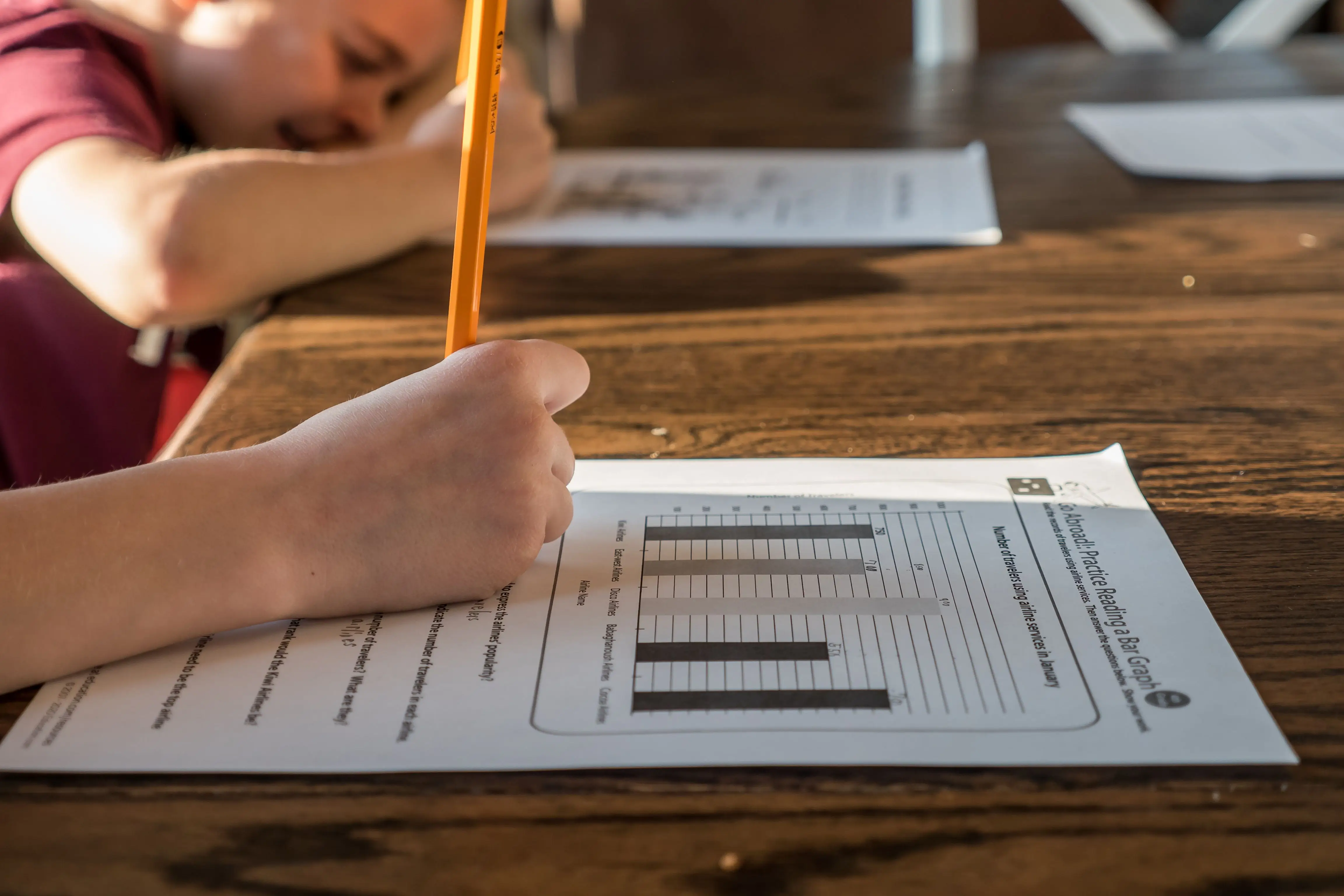 Student answering practice questions and reviewing notes at a study desk 